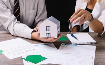 Équipe d'agence immobilière présentant maquette de maison et documents contractuels lors d'une transaction